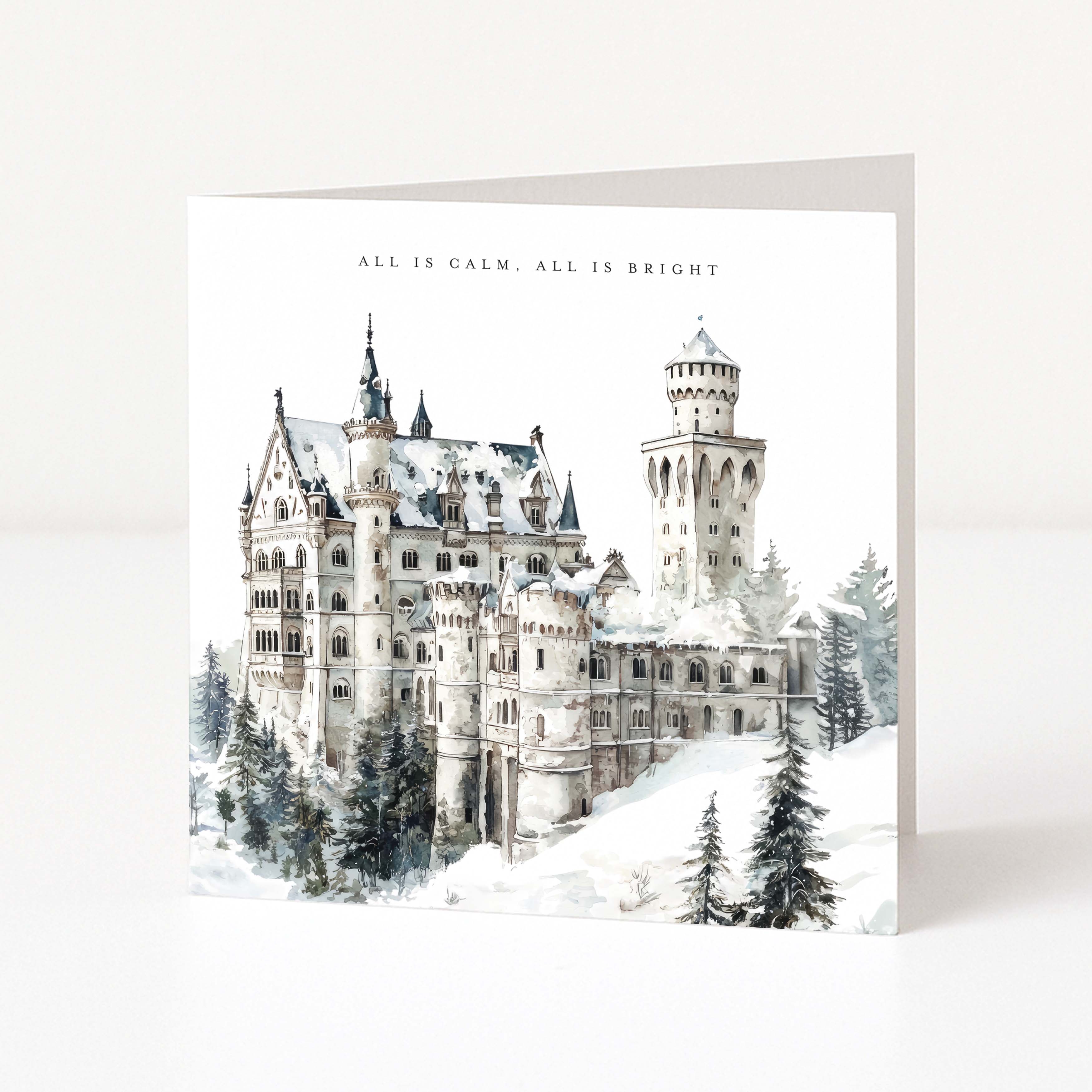 A square greeting card featuring a watercolour-style winter illustration of a snow-covered castle with the text 'ALL IS CALM, ALL IS BRIGHT' at the top, photographed on a clean white background.