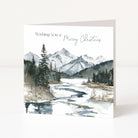 A square Christmas greeting card standing upright on a white surface. The front features a watercolor-style winter landscape with snowy mountains, evergreen trees, and a partially frozen river, with the text 'Wishing you a Merry Christmas' printed at the top.