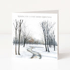 A square Christmas greeting card standing upright on a white surface. The card features a watercolor winter landscape with bare trees, snow, and a winding path, with the text 'WISHING YOU A VERY MERRY CHRISTMAS' printed at the top.