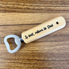 Wooden bottle opener with engraved text on a wooden surface