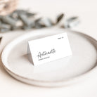 A place card for a wedding with elegant typography on a stone plate with foliage background