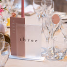 Decorated table setting with flowers, glasses, and a menu card on a white tablecloth.