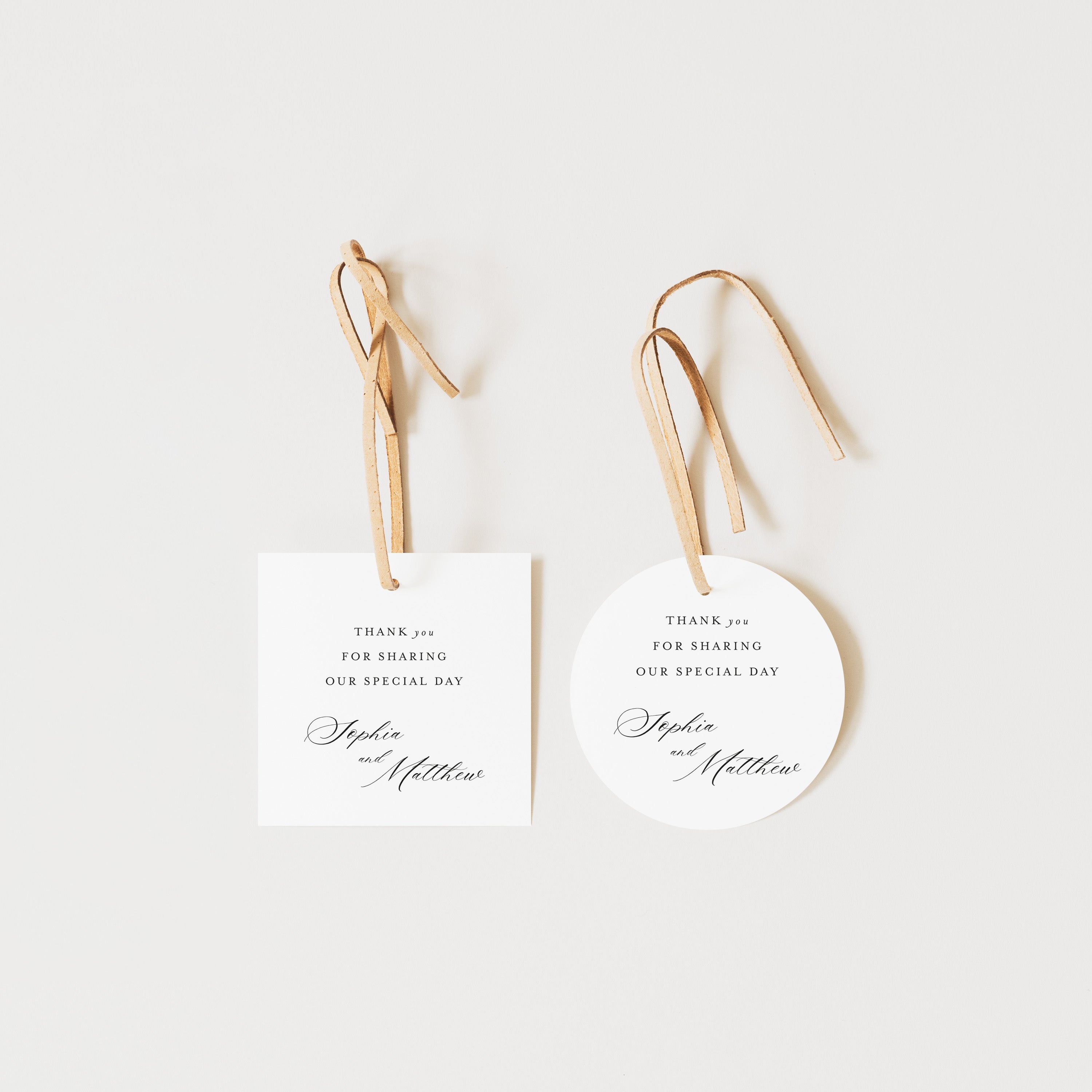 Two white tags with gold text and ribbons on a light beige background