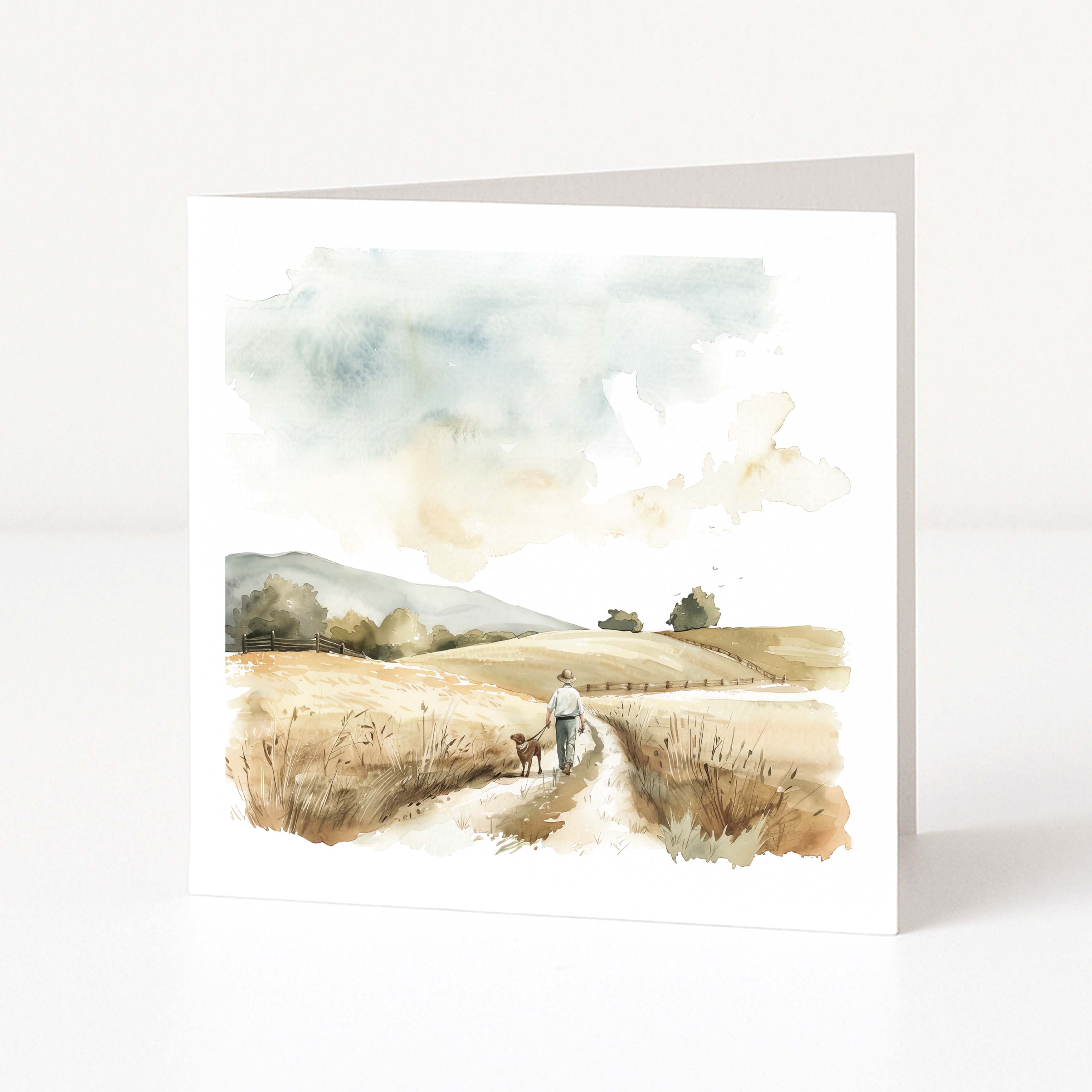 Greeting card with a landscape design of a person walking a dog in a field.