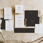 Wedding invitation suite with black and white cards on a textured surface