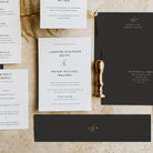 Wedding invitation set with RSVP card and gold wax seal on a textured surface