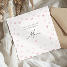 Greeting card with 'Happy Mother's Day to a very special Mum' text and heart patterns, accompanied by a brown envelope on a textured surface.