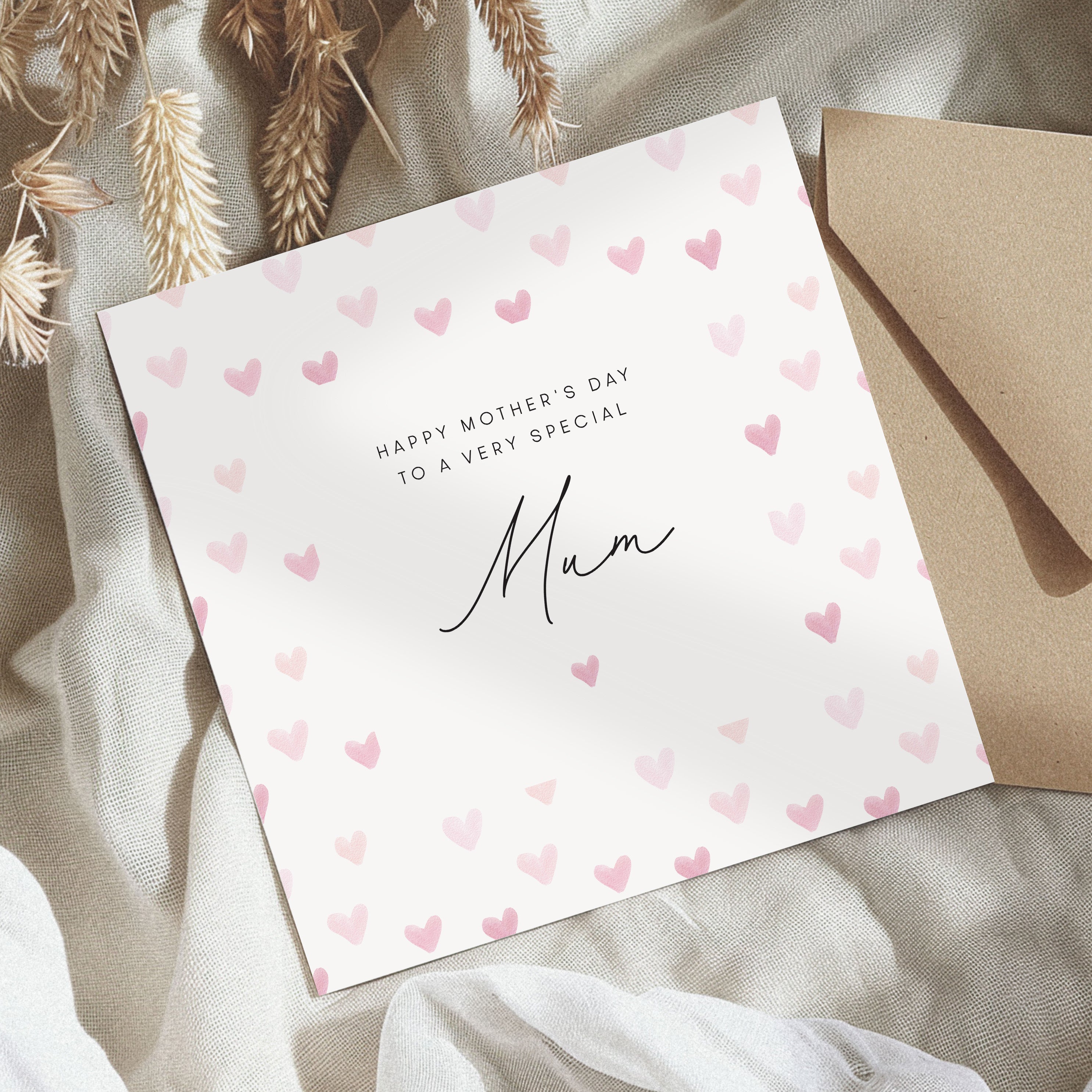 Greeting card with 'Happy Mother's Day to a very special Mum' text and heart patterns, accompanied by a brown envelope on a textured surface.