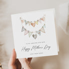 Greeting card with heart-shaped bunting design and personalized text, held by a hand.