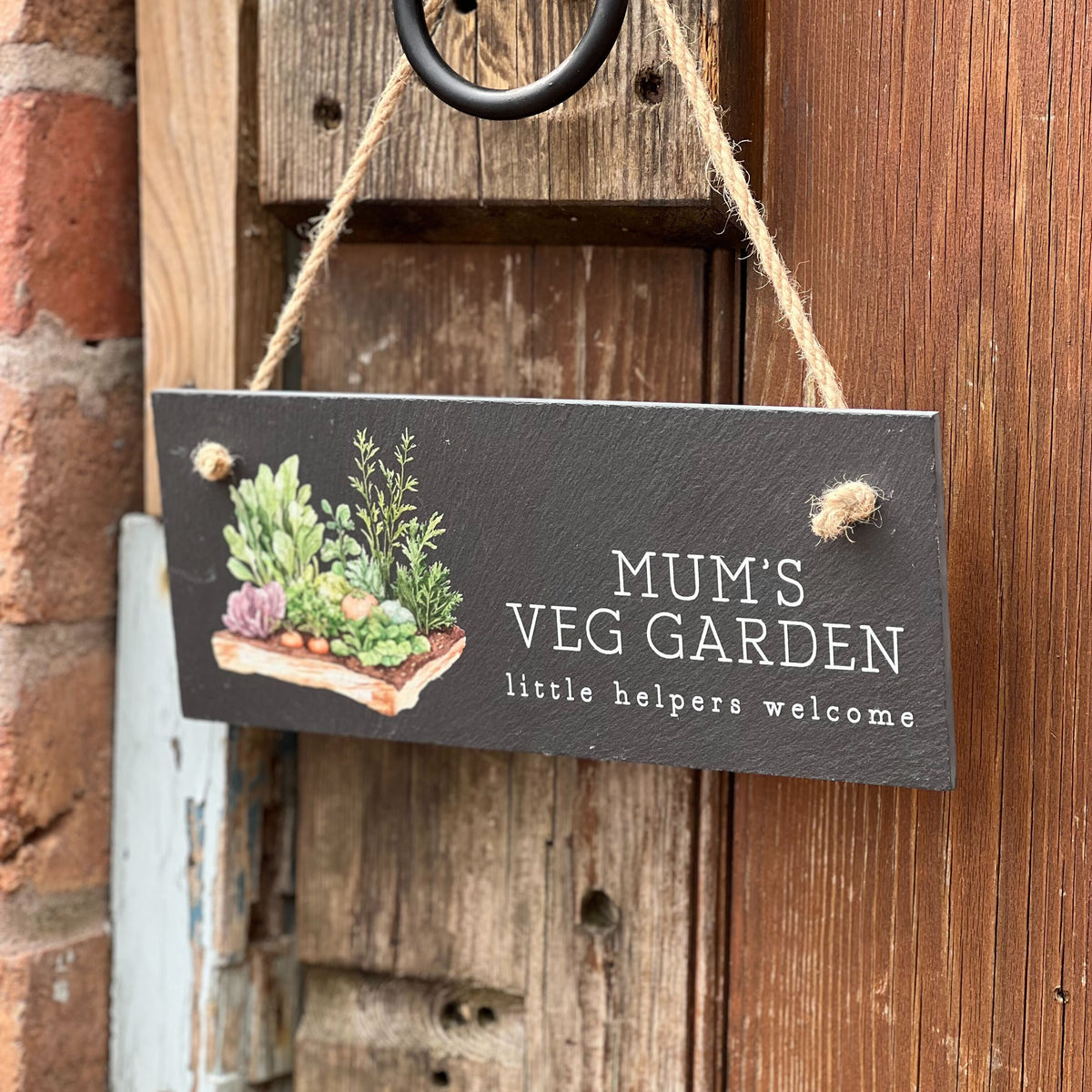 Decorative sign for 'Mum's Veg Garden' hanging on a wooden door.