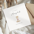 Greeting card for a special 'Mummy to be' on Mother's Day with a giraffe illustration, placed on a textured fabric background.