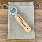 Wooden bottle opener with engraved text on a fabric pouch