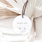 Round white tag with 'Thank You' and initials, tied with a string against a neutral background.