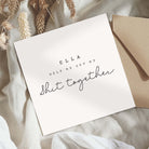 White card with text 'ELLA HELP ME GET MY SHIT TOGETHER' on a textured surface with an envelope.
