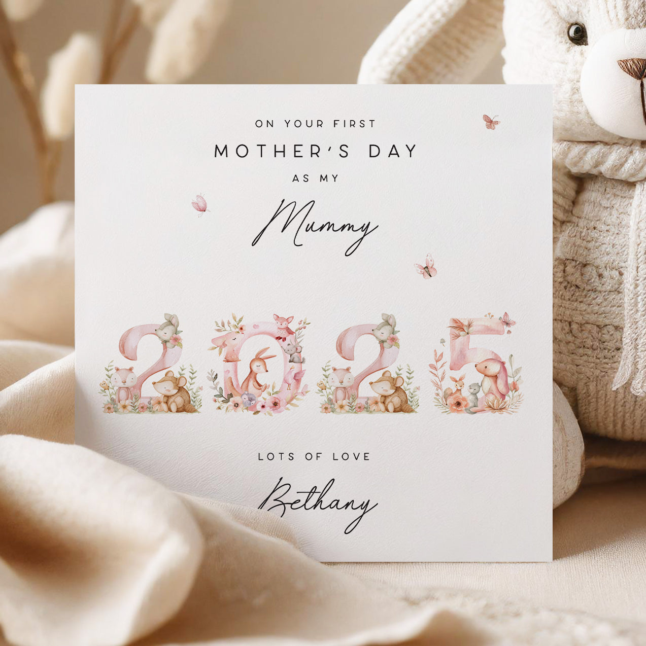 Greeting card for first Mother's Day with floral numbers and teddy bear illustrations, placed on a soft surface.