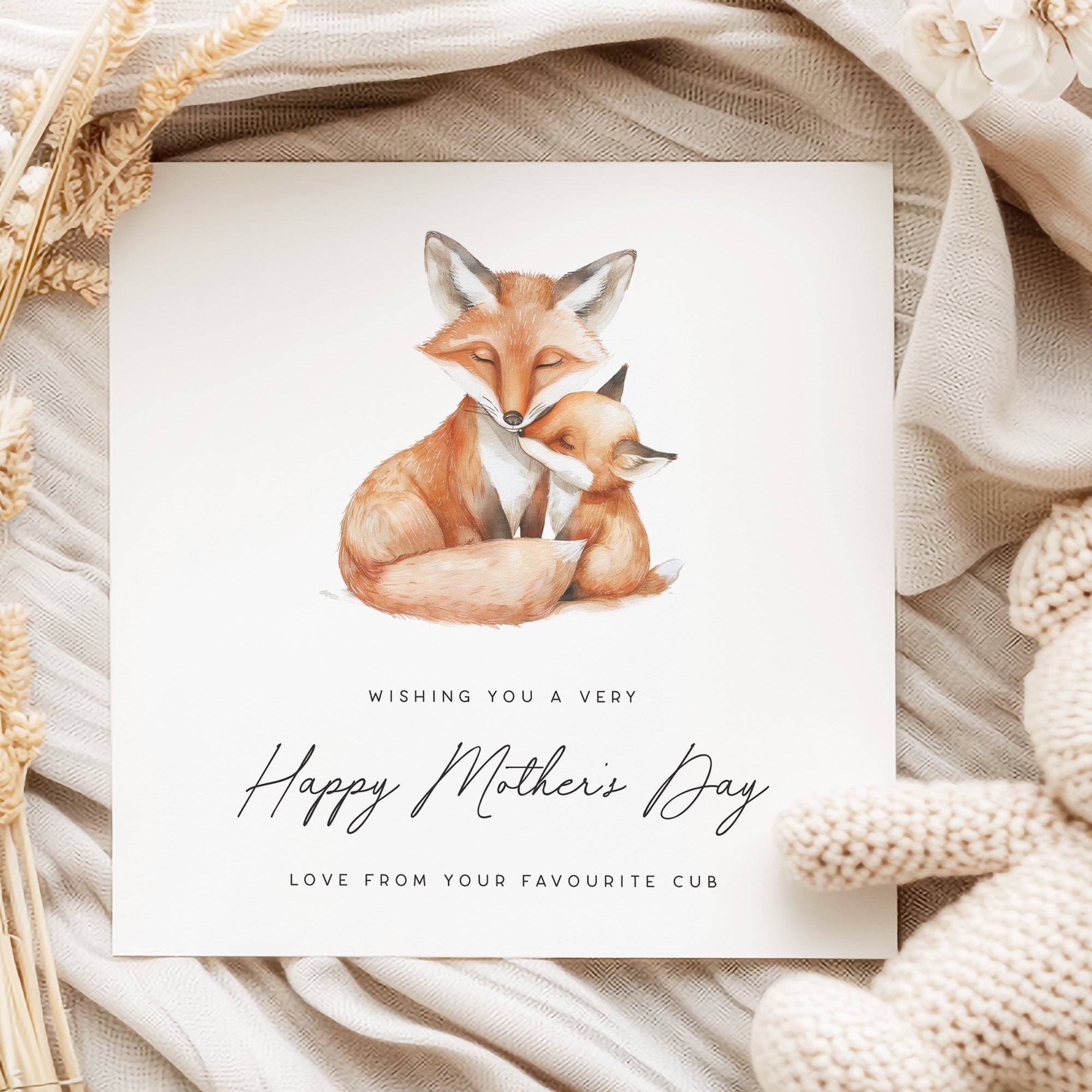 Greeting card with fox illustration and 'Happy Mother's Day' text on a textured fabric background.