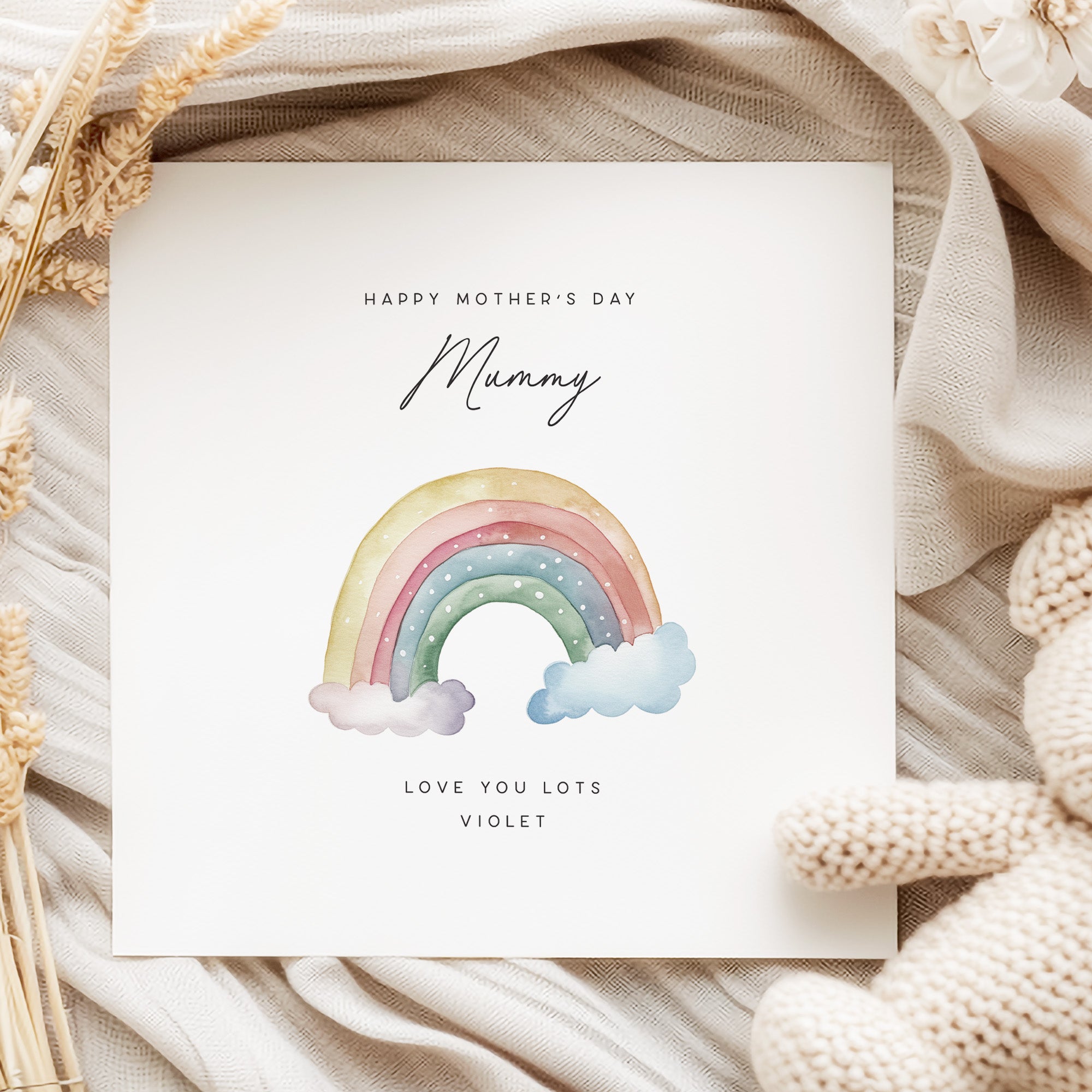 Mother's Day card with a rainbow and 'Mummy' text on a textured fabric background.