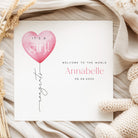 New baby card with pink heart balloon and text on a soft fabric background