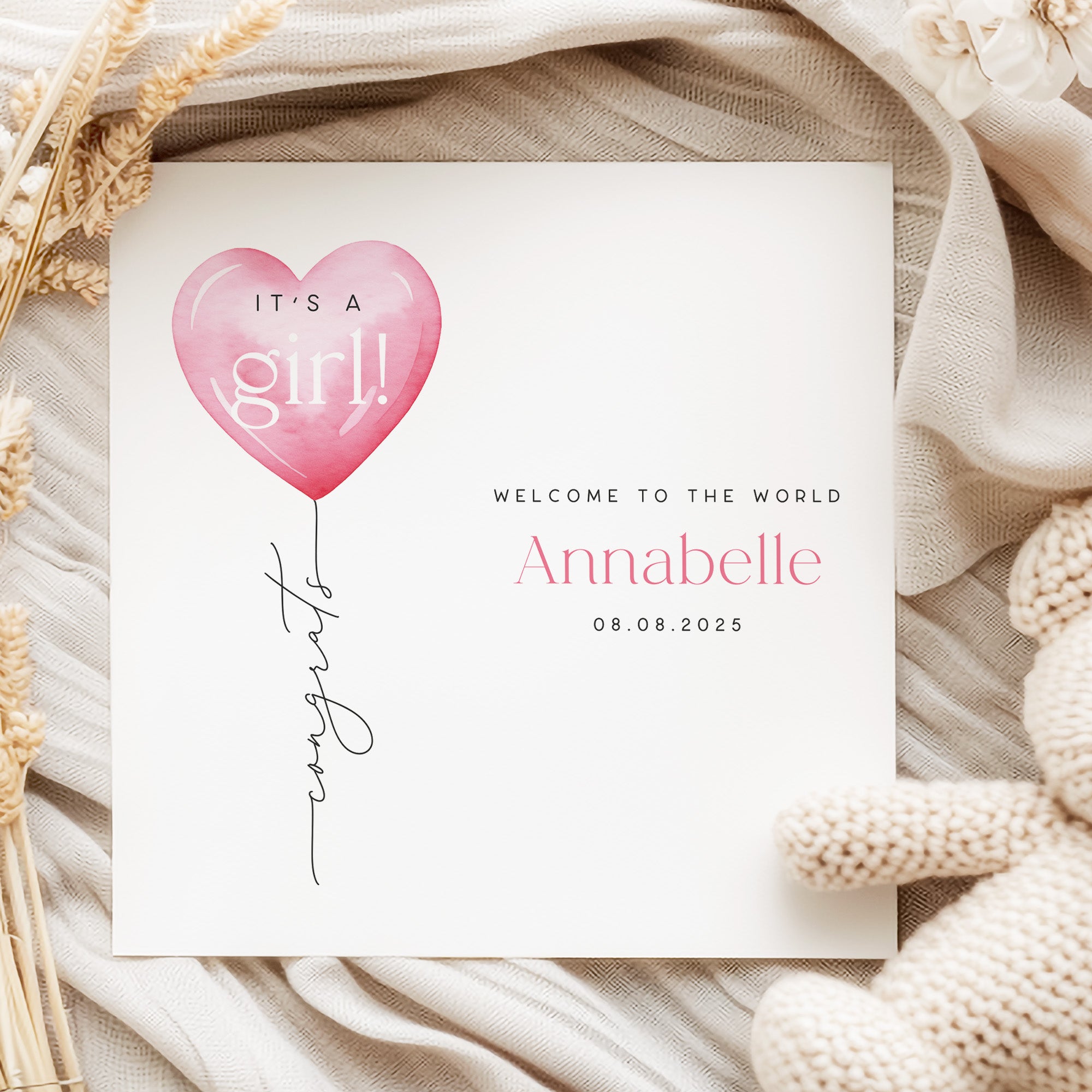 New baby card with pink heart balloon and text on a soft fabric background