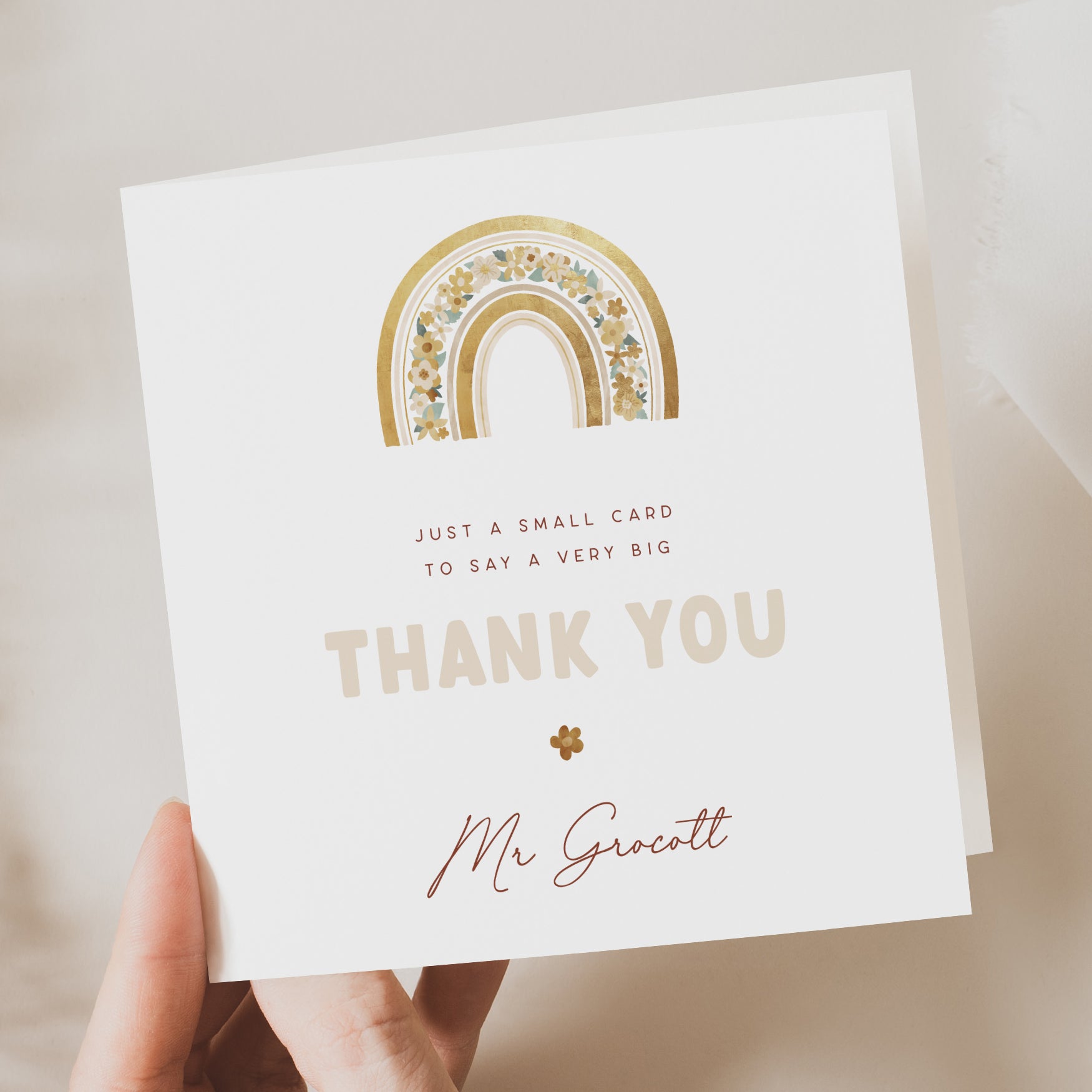 White card with gold rainbow design and 'Thank You' message held by a hand.