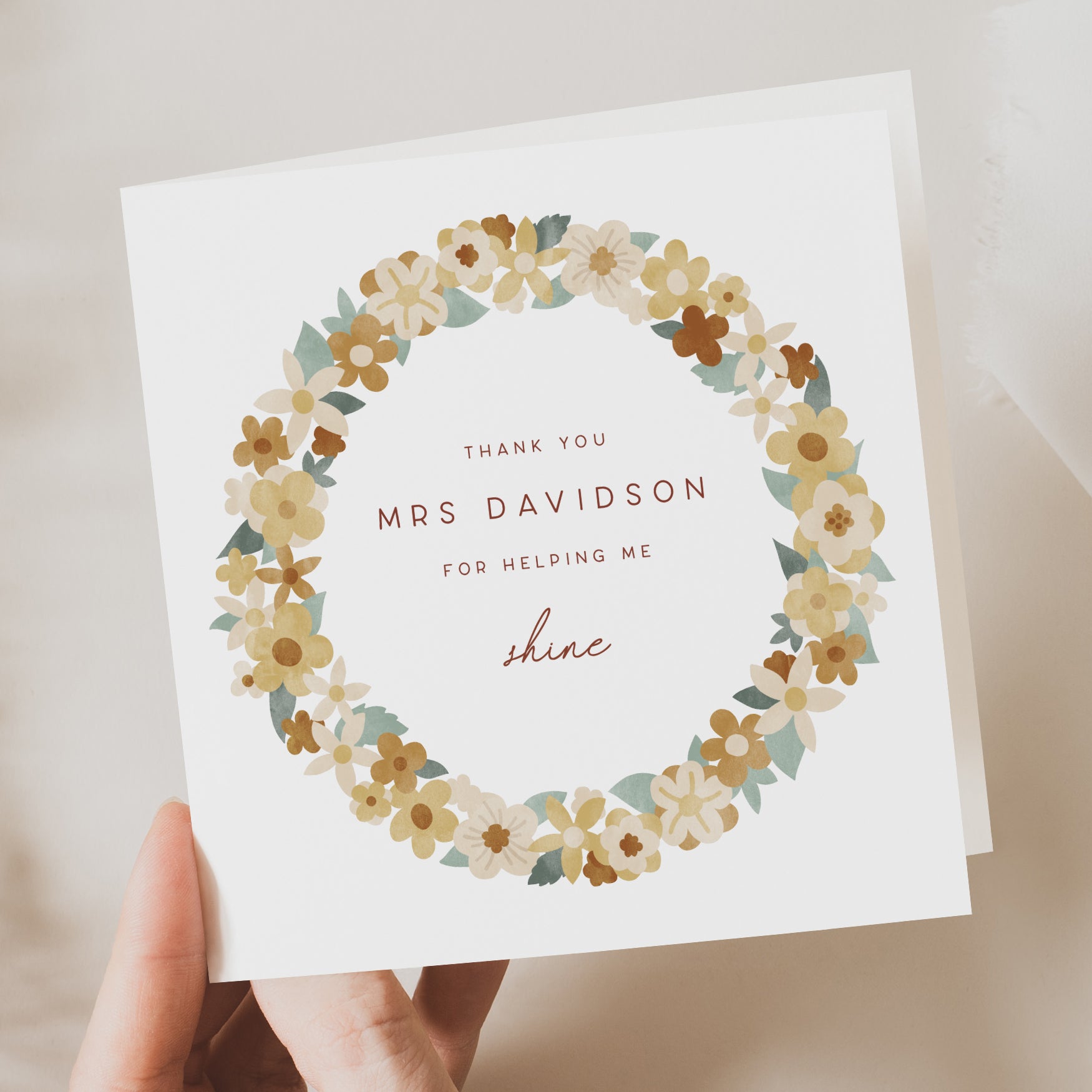 Greeting card with floral design and text held by a hand on a neutral background