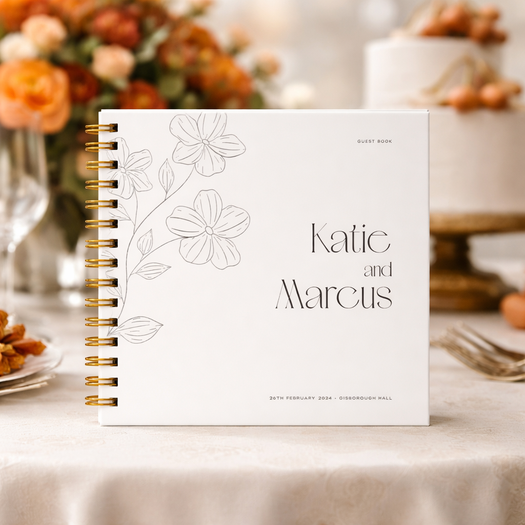 white guest book with gold binder on a table with autumn wedding flowers and cake