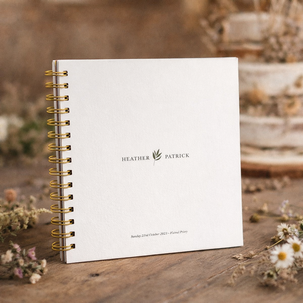 white guest book with gold binder on a wooden table with wildflowers