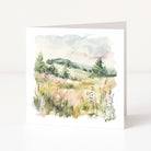 Greeting card with a watercolor landscape of a field and trees on a white background