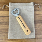 Wooden bottle opener with metal cap on a gray drawstring bag on a wooden surface