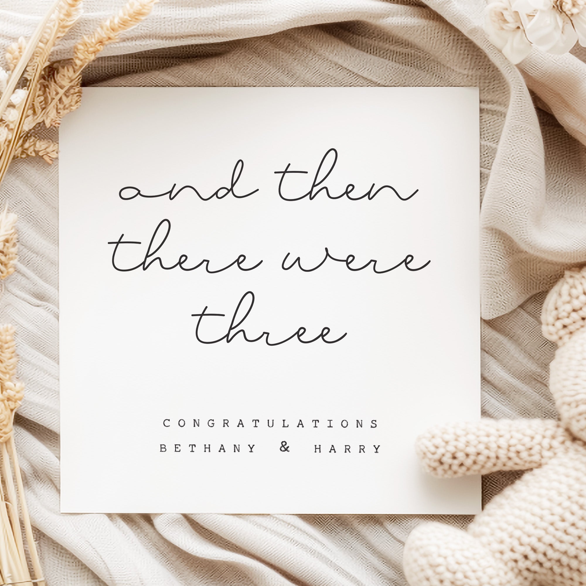 Greeting card with 'and then there were three' text on a textured fabric background
