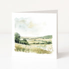 Framed watercolor landscape painting of a field with trees and a sunset.