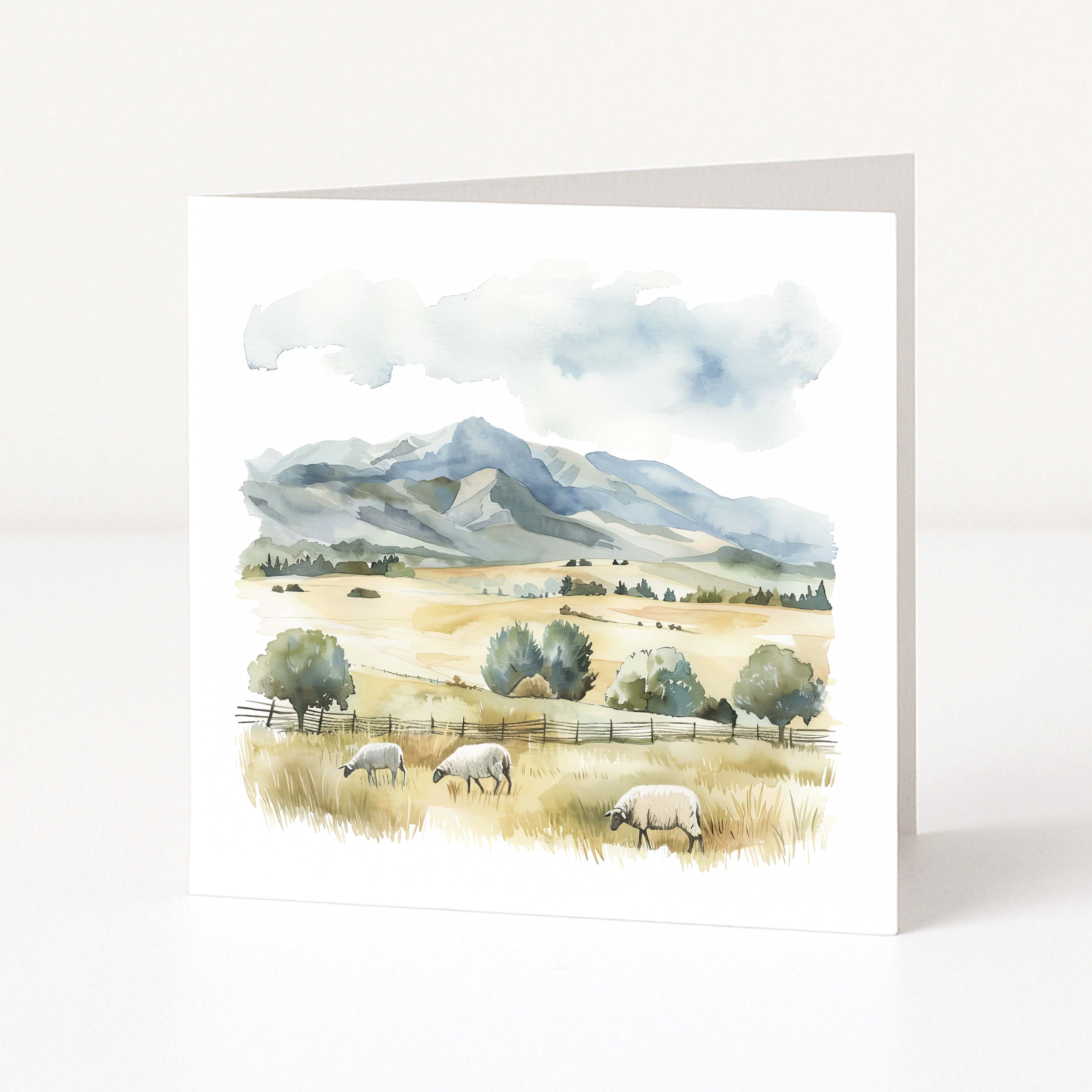 Greeting card with a scenic landscape featuring mountains, trees, and sheep on a white background.