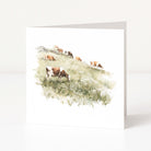 Greeting card with a watercolor illustration of cows in a field on a white background