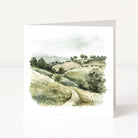 Greeting card with a watercolor landscape of rolling hills and trees on a white background