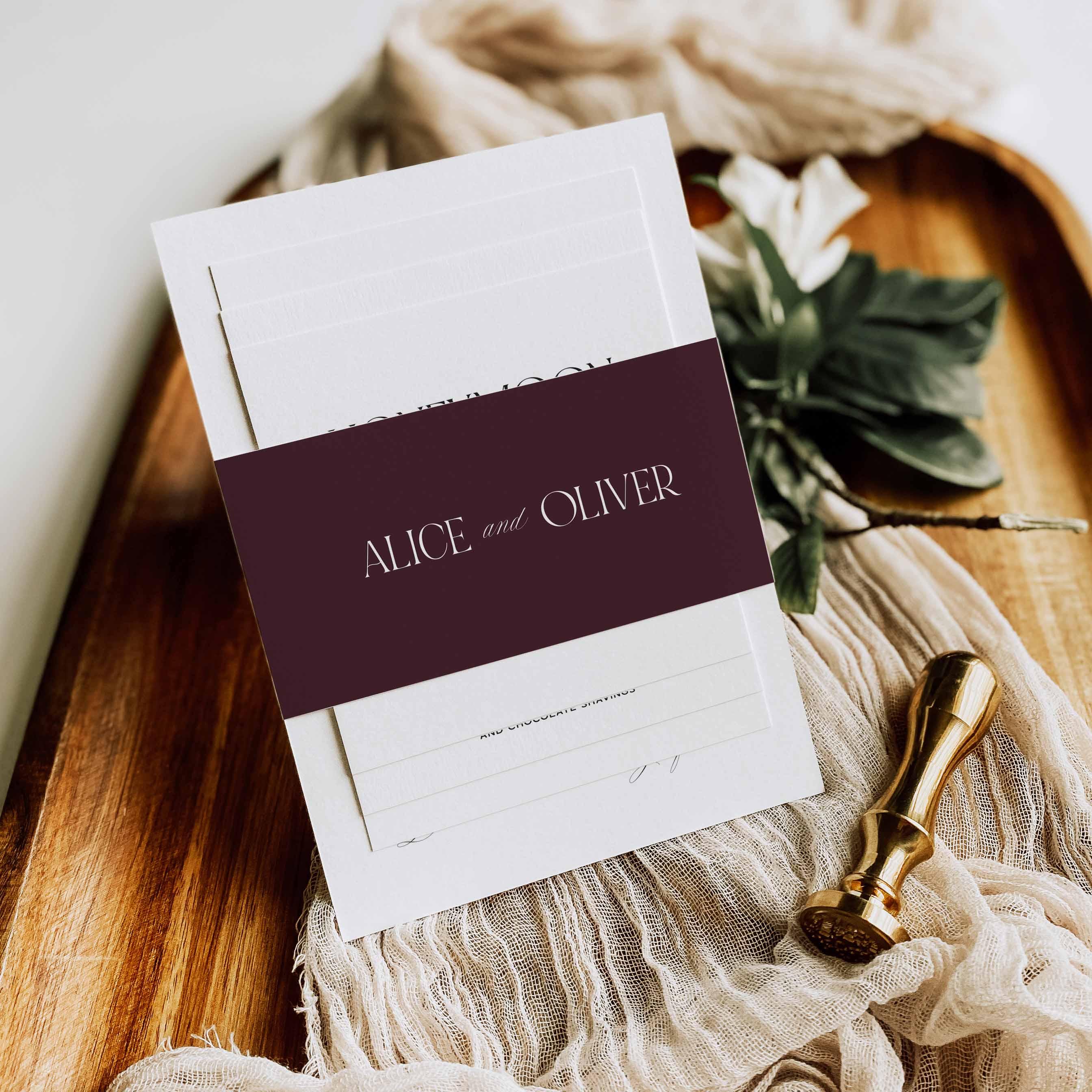 Wedding invitation set with 'Alice and Oliver' on a wooden surface with decorative elements.