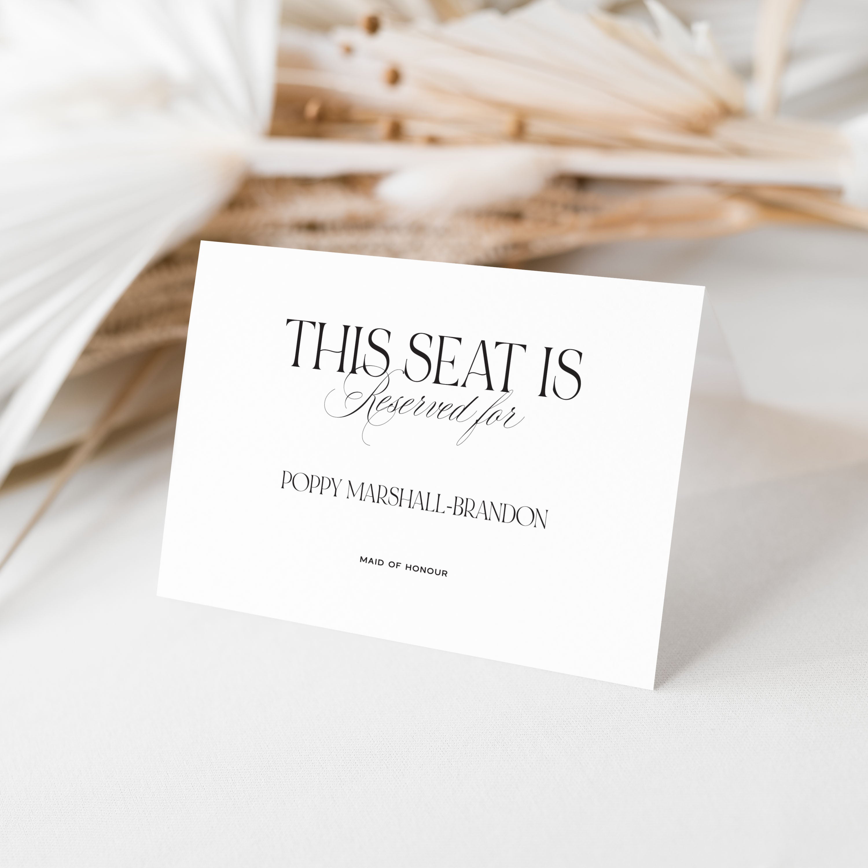 Wedding Reserved seat card for Maid of Honour on a white surface with dried plants in the background