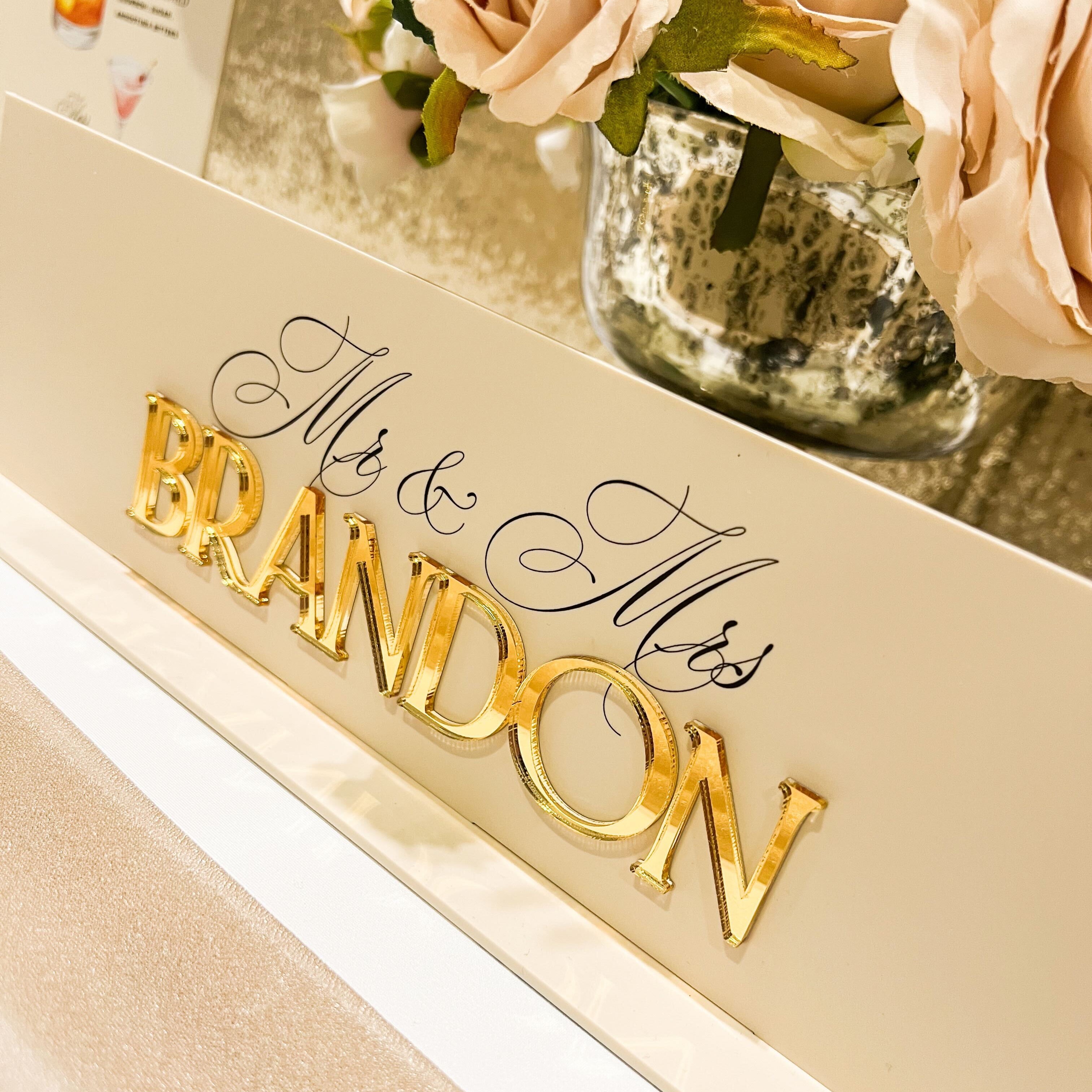 Decorative sign with 'Mr & Mrs Brandon' on a table with flowers