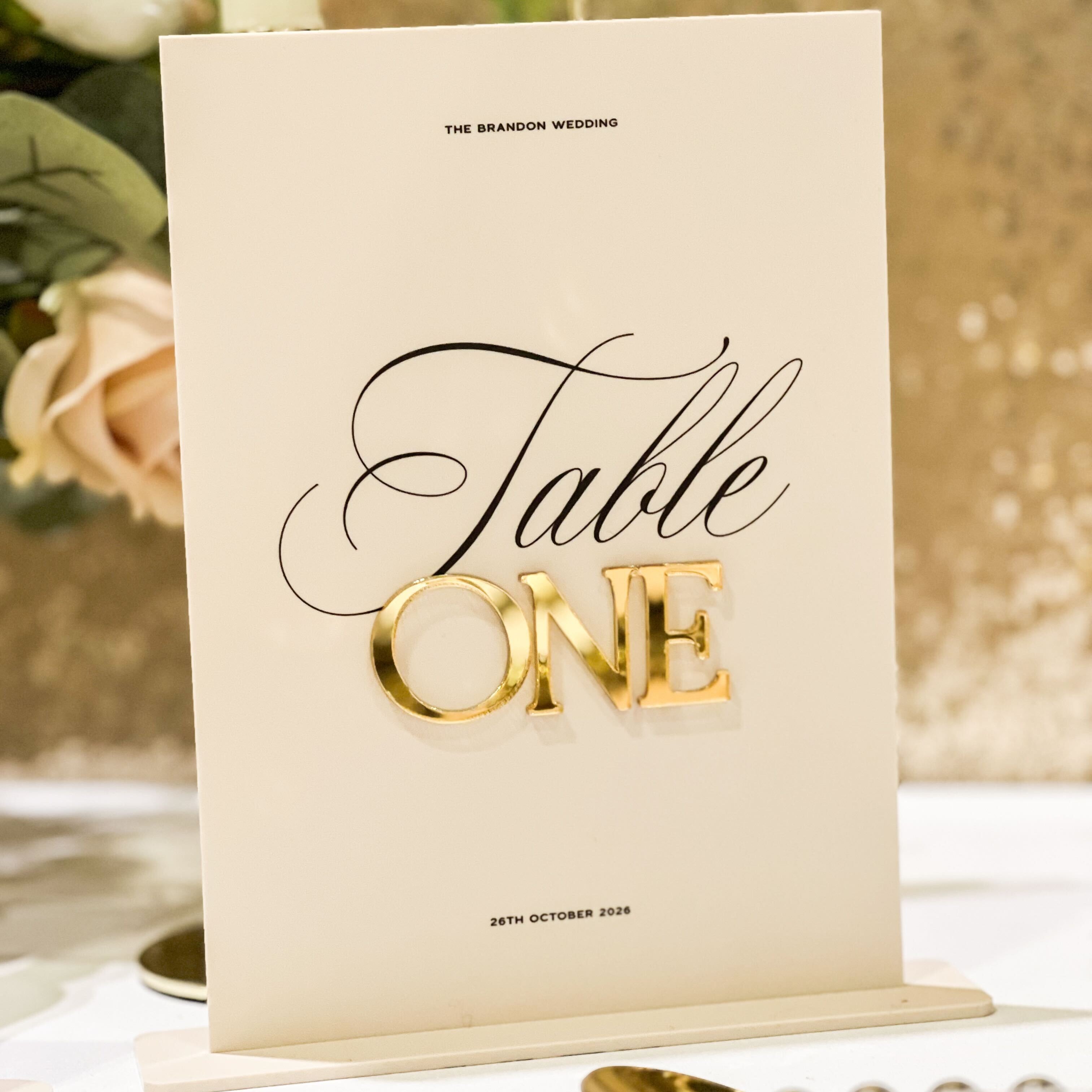 Table number card for 'Table One' with gold text on a decorative background