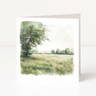 Greeting card with a watercolor design of a tree and field on a white background