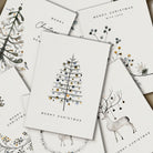 Collection of Christmas cards with tree, deer, and floral designs on a white background.