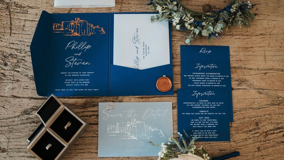 Wedding invitation set with navy blue envelope, card, and details on a wooden surface.