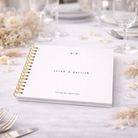 White wedding guest book on a wedding table with champagne flowers and glassware