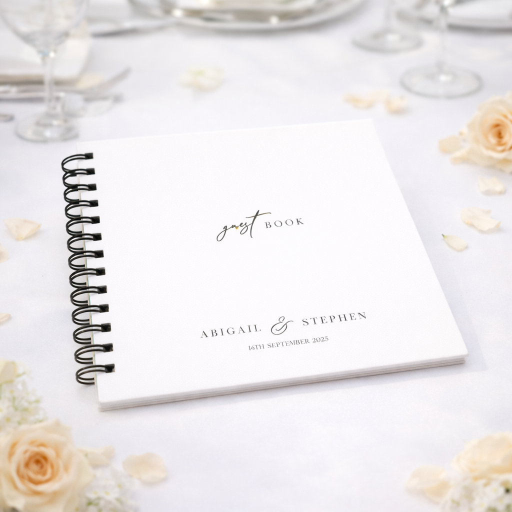 Wedding guest book with personalized text on a table with flowers and glasses