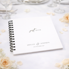 Wedding guest book with personalized text on a table with flowers and glasses