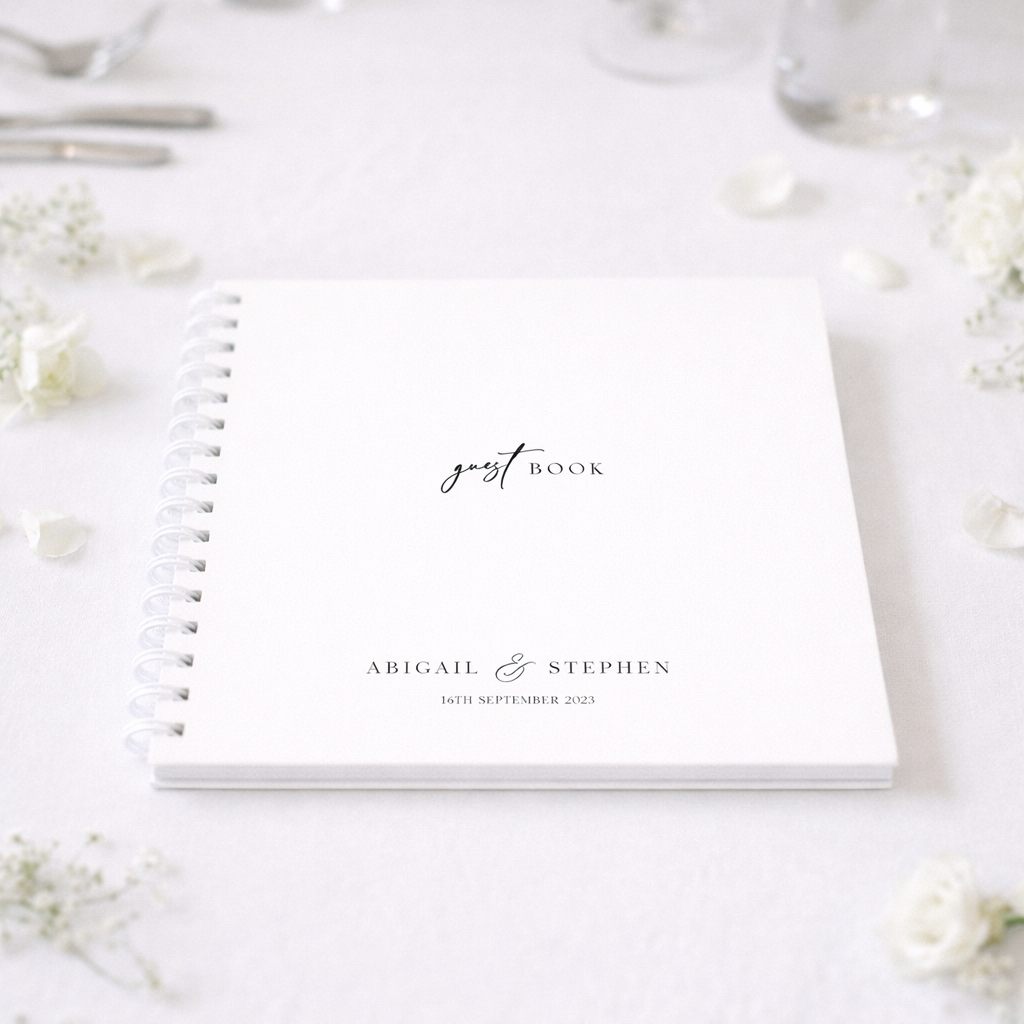 White guest book with personalized text on a white surface with flowers