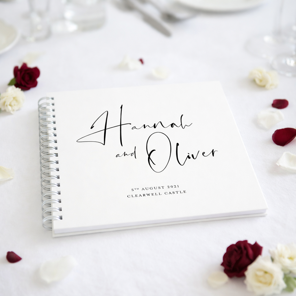 Spiral-bound guestbook with 'Hannah and Oliver' on a white surface with flowers