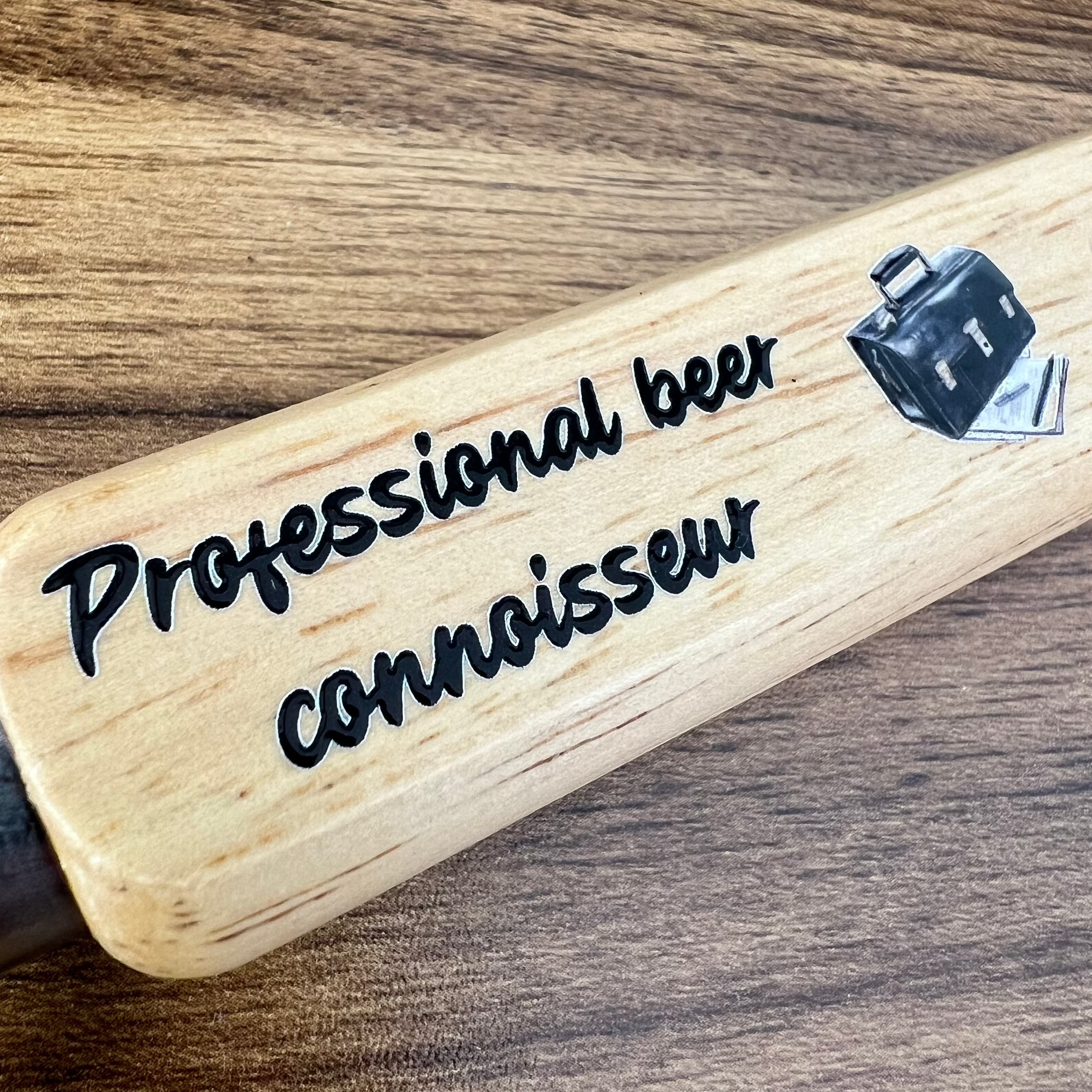 wooden bottle opener with professional beer connoisseur printed on the handle up close