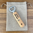 Wooden bottle opener with 'World's Best Dad' engraving on a fabric pouch.