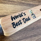 Wooden bottle opener with 'World's Best Dad' engraving on a wooden surface