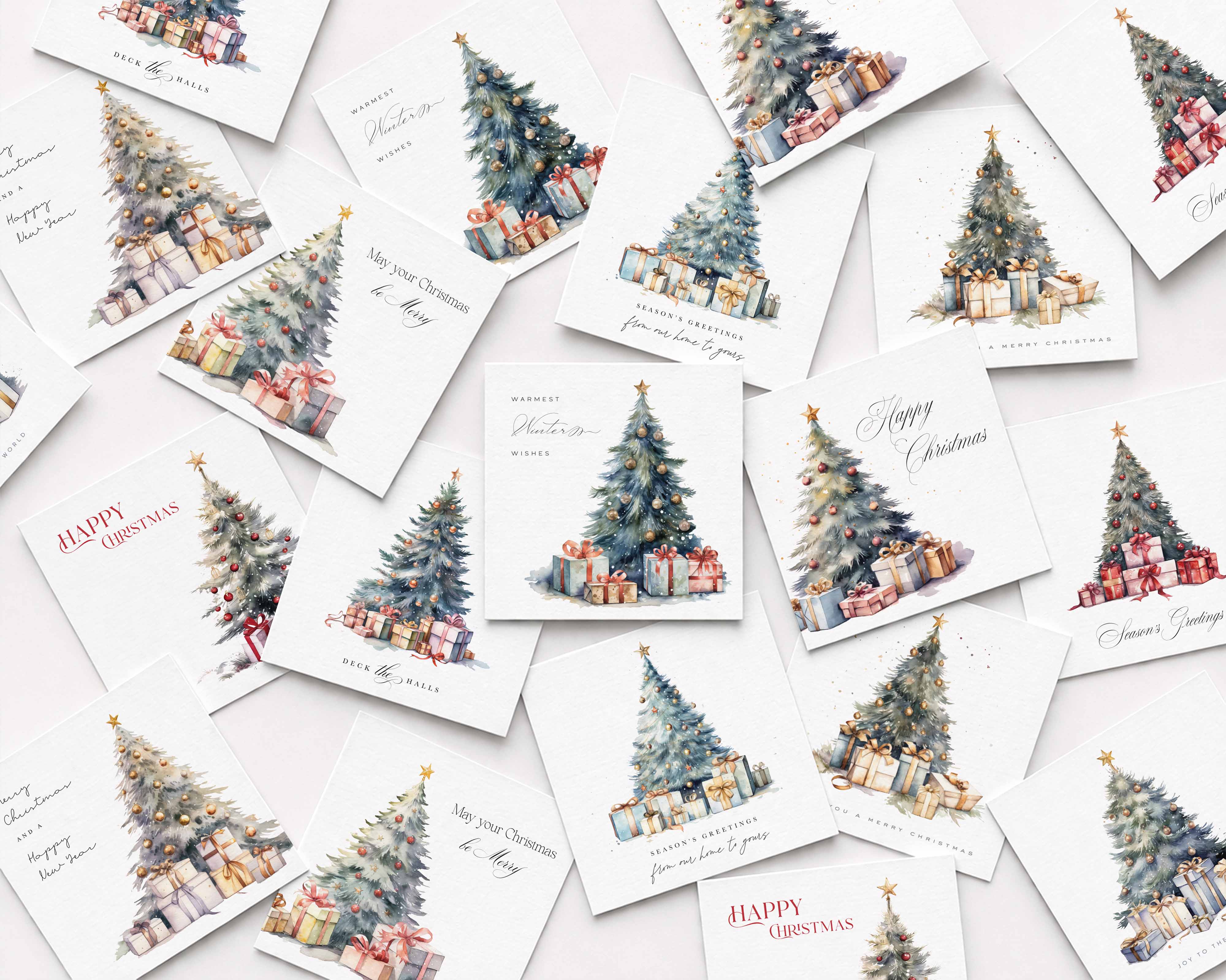 A flat-lay arrangement of multiple white Christmas greeting cards scattered on a light background. Each card features a watercolor illustration of a decorated Christmas tree with wrapped presents, with holiday greetings such as 'Happy Christmas' and 'Merry Christmas' in elegant script.